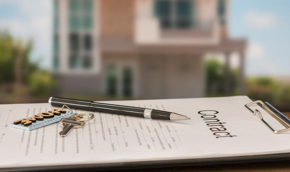 Pen And House Key On A Contract With A Property Background